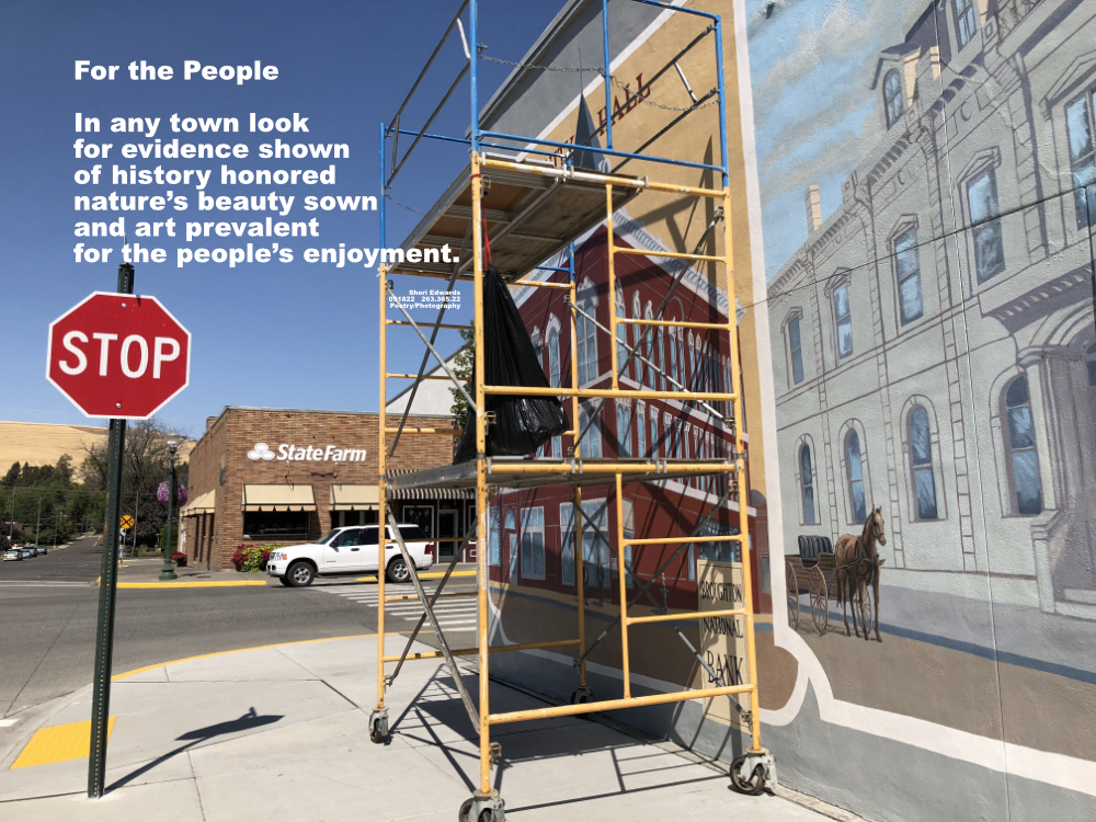 Dayton, WA in 2018 restoration of historical murals by Don Brown; scaffold in front of mural; Office across the street with flowers blooming