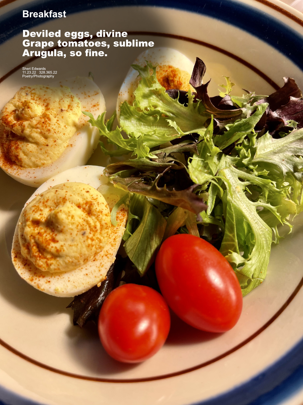 breakfast: deviled eggs, grape tomatoes, arugula on a tan plate with navy band around edge