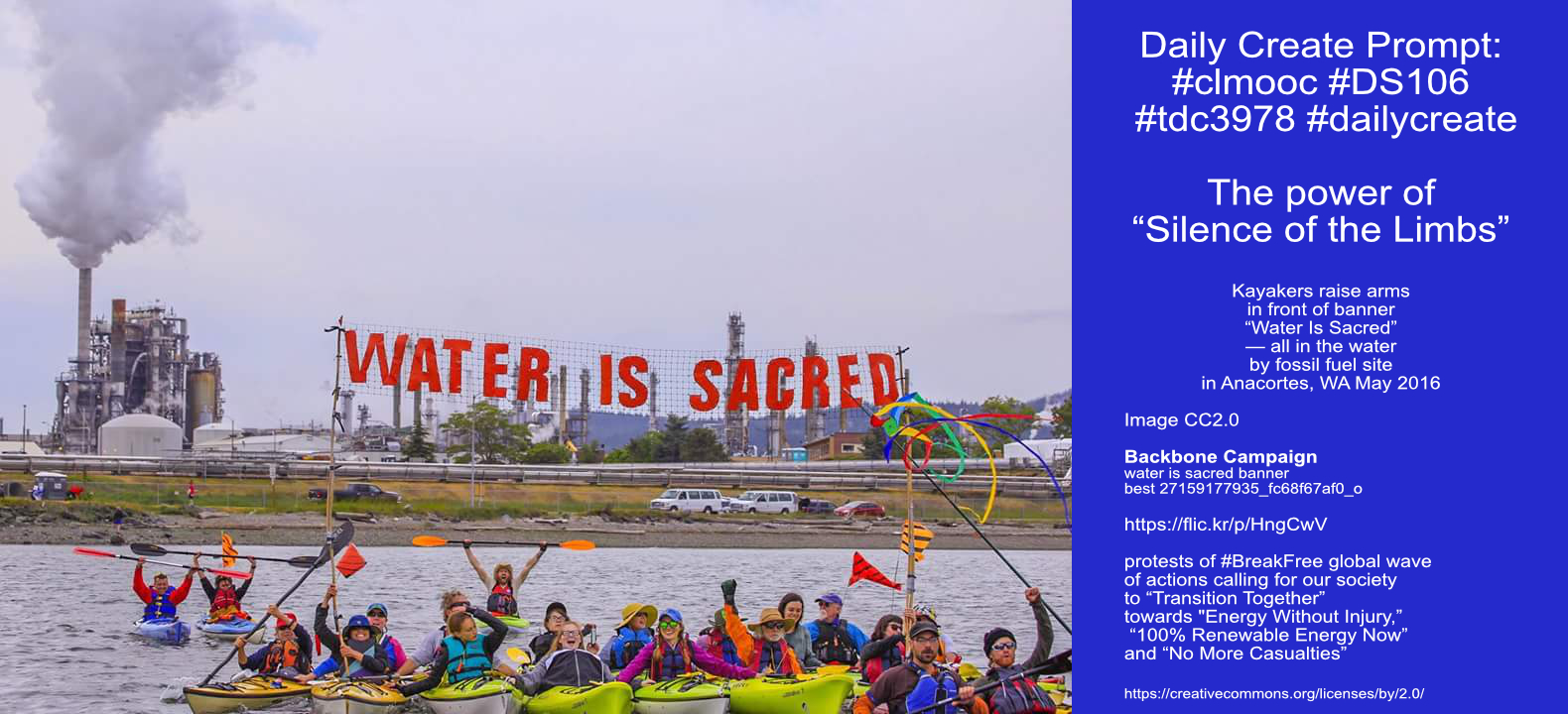 Kayakers raise arms in front of banner “Water Is Sacred”— all in the water by fossil fuel site in Anacortes, WA May 2016
