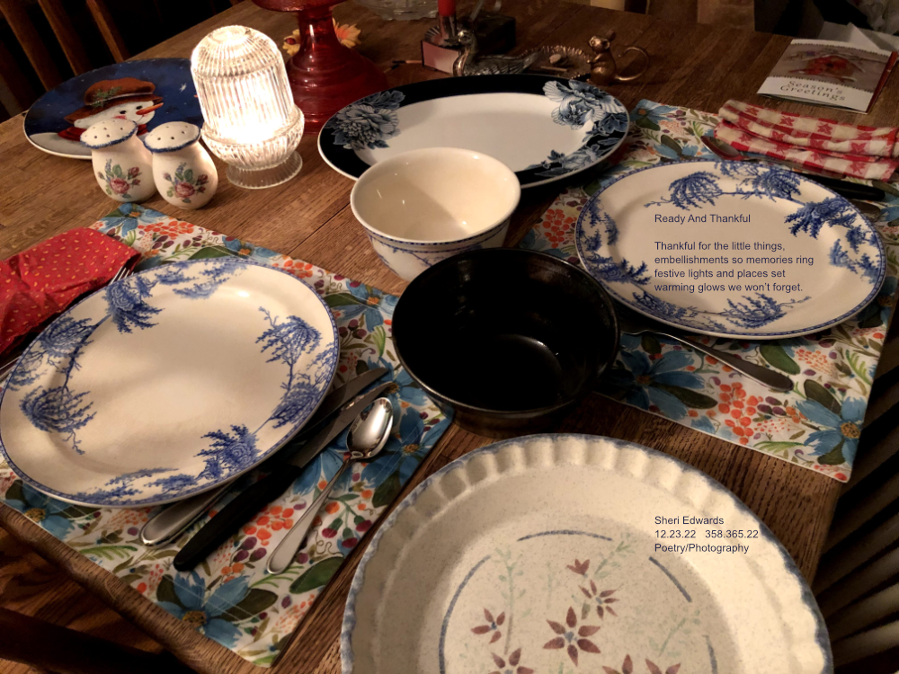 Place settings of various plates ready for a holiday meal with candle glowing