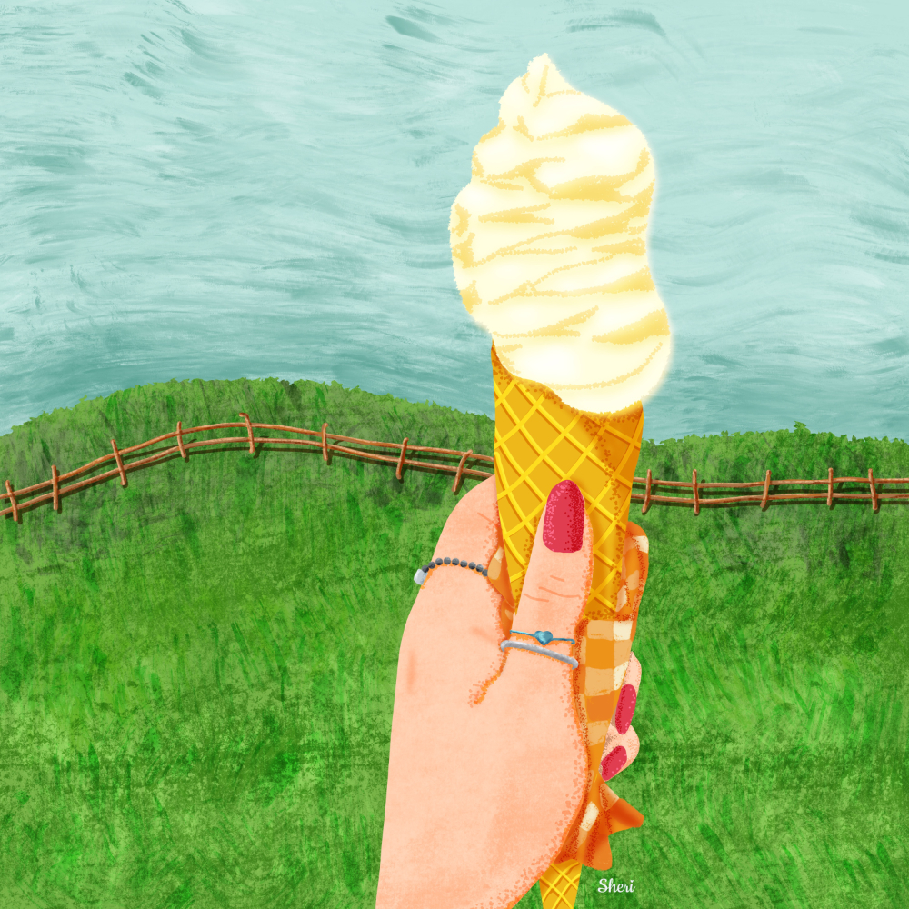 Ice cream cone wrapped in checkered napkin held up to grassy landscape in a hand with red fingernails