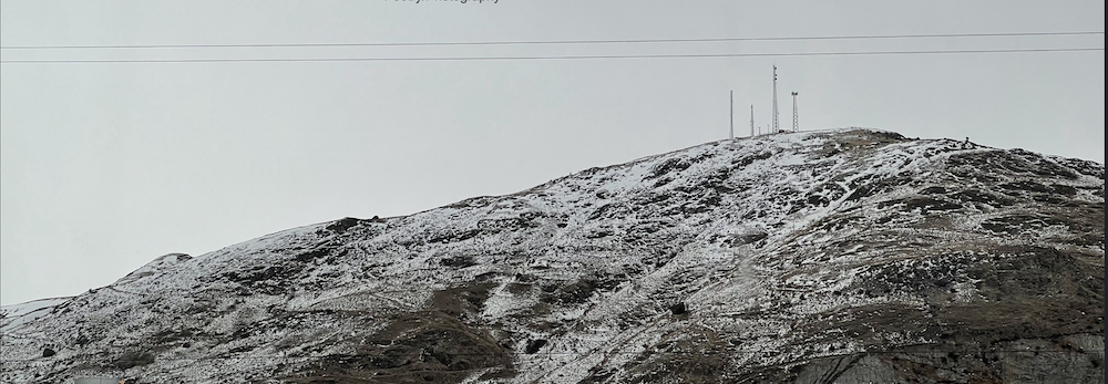 overcast day over snow spotted hillside with microwave towers