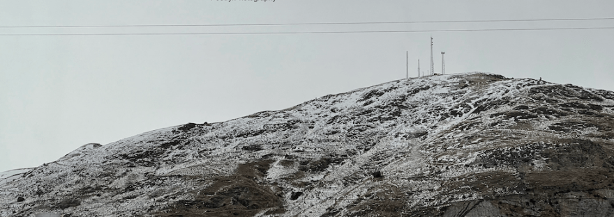 overcast day over snow spotted hillside with microwave towers