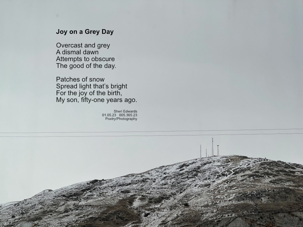 an overcast hillside spotted with snow with microwave towers; two power lines flow across the lower third of the shot