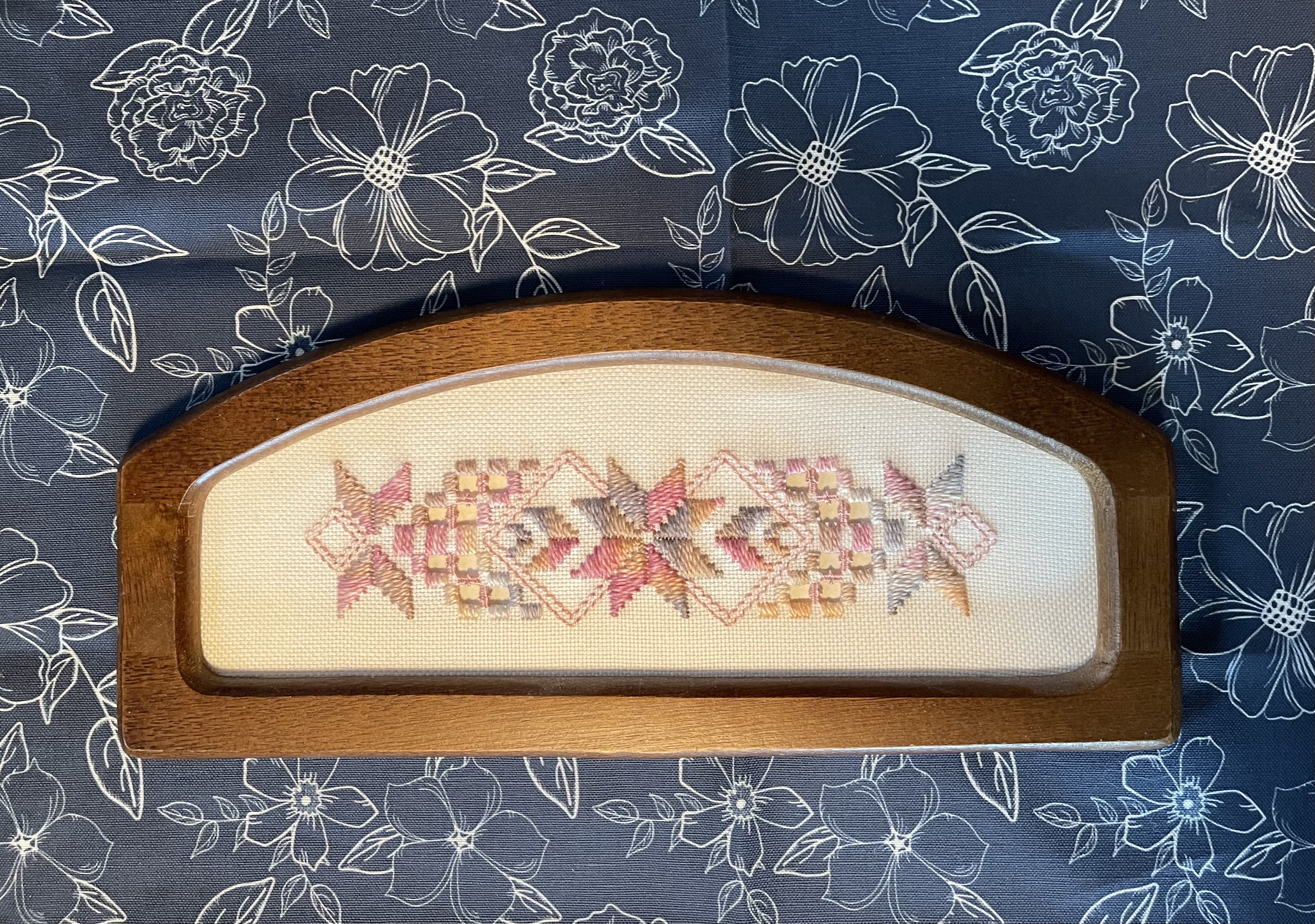 My Aunt Marj’s Hardanger in wooden frame atop my art as placement in white outlined flowers on navy background