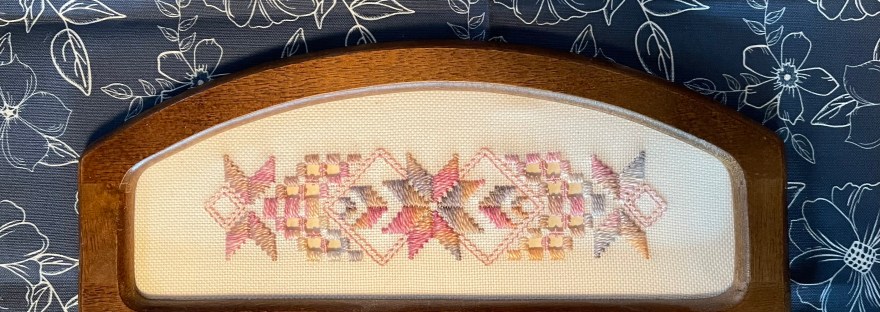 My Aunt Marj’s Hardanger in wooden frame atop my art as placement in white outlined flowers on navy background