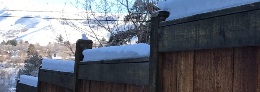 snow piled on top of a fence