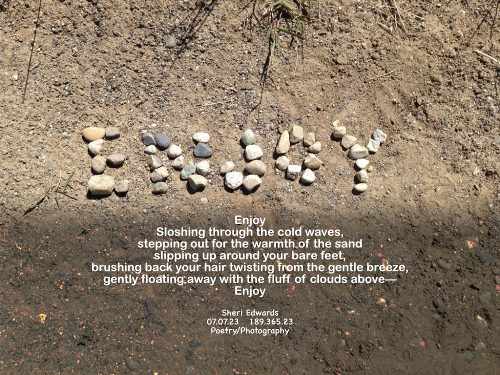 Rocks on the beach arranged into the word, “Enjoy.”