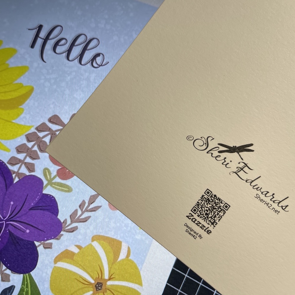 Part of front of "Hello" floral card and the back of the card with logo and signature