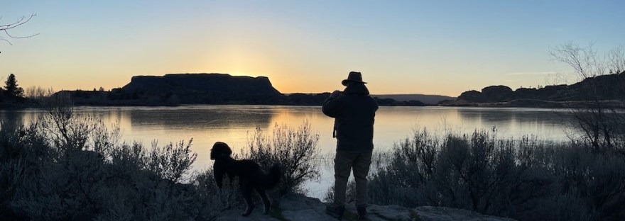 a man and his dog in the setting sun in a landscape formed from fire and ice.