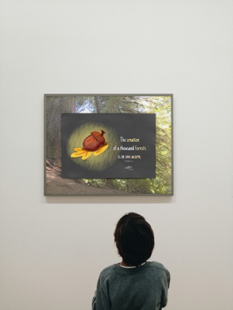mockup inside forest photo with boy looking at it: poster inside frame --acorn on oak leaf with quote "The creation of a thousand forests is in one acorn. Ralph Waldo Emerson; by Sheri42